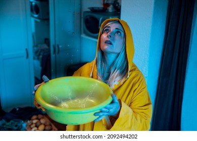 Woman In Yellow Raincoat Collecting Water Leak From The Ceiling. A Roof Leak At Night During The Storm. Catching Water Drop Splash To A Pot