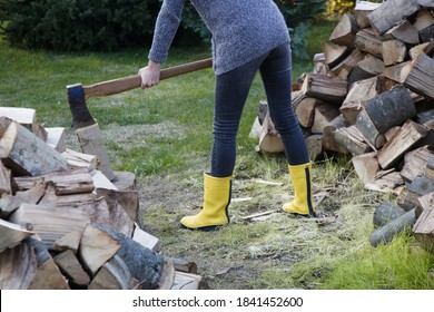 Woman In Yellow Rubber Boots Chopping Woods With Axe. Homestead Chores For The Fall On Farm.