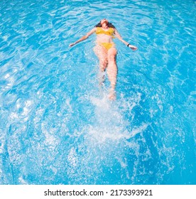 Woman In Yellow Swimming Suit In Clear Blue Water In Pool