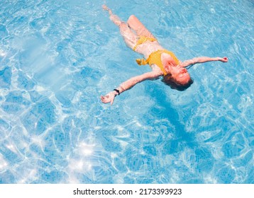 Woman In Yellow Swimming Suit In Clear Blue Water In Pool