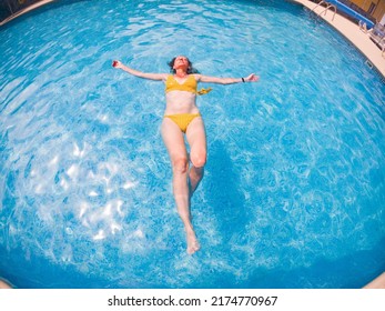 Woman In Yellow Swimming Suit In Clear Blue Water In Pool