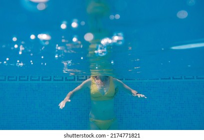 Woman In Yellow Swimming Suit In Clear Blue Water In Pool