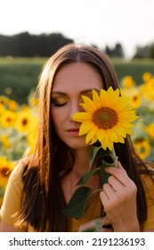 Woman In Yellow T-shirt With Sunflower In Her Hand On The Field. Yellow Eye Shadow And Manicure.