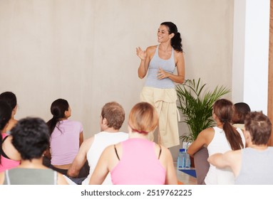 Woman, yoga instructor and talk with group, class or presentation for health, wellness and advice for self care. Personal trainer, coach and people in audience, floor and mock up space at studio - Powered by Shutterstock