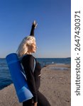 Woman Yoga Mat Beach - A blonde woman practices yoga on a beach with a blue yoga mat.