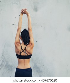 Woman In Yoga Pants And Sport Bra Stretching Back