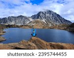 Woman yoga pose meditating on rock by blue mountain lake. Lake Ingalls. Leavenworth. WA. USA