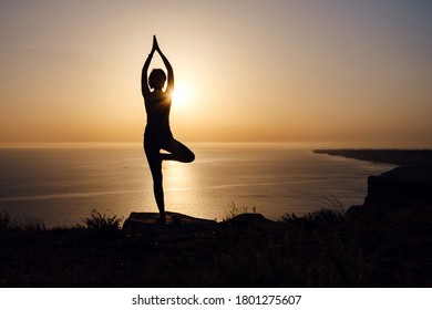 The woman with yoga posture on the mountain at sunset Silhouette of gorgeous young woman practicing yoga outdoor. wellness, healthcare, sport and lifestyle concept - Powered by Shutterstock