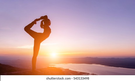 The Woman With Yoga Posture On The Mountain At Sunset; Silhouette Of Gorgeous Young Woman Practicing Yoga Outdoor.
