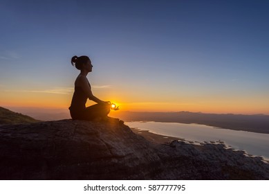 The Woman With Yoga Posture On The Mountain At Sunset; Silhouette Of Gorgeous Young Woman Practicing  Lotus  Yoga Outdoor.