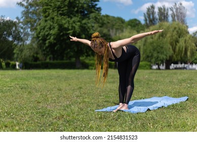 Woman yogi with dreadlocks stretching doing practicing standing Ardha Uttanasana half forward pose on yoga mat. Relaxing in the morning. Fitness instructor coach showing exercises 