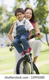 Woman And Young Boy On A Bike Outdoors Smiling