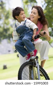 Woman And Young Boy On A Bike Outdoors Smiling