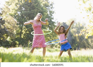 Woman and young girl outdoors using hula hoops and smiling - Powered by Shutterstock