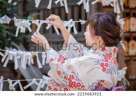 A woman in a yukata tying an omikuji