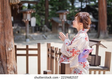 A Woman In A Yukata Worshiping At A Sacred Tree