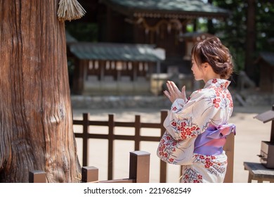 A Woman In A Yukata Worshiping At A Sacred Tree