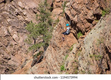 Woman ziplining down a cliff in the Rocky Mountains of Colorado - Powered by Shutterstock