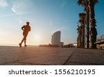 Womand running in Barcelona promenade at sunrise - Female silhouette doing jogging early for morning routine - Fitness, sport, travel and healthy lifestyle concept - Soft focus on body