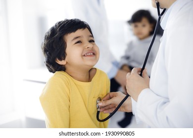 Woman-doctor examining a child patient by stethoscope. Cute arab boy at physician appointment. Medicine help concept - Powered by Shutterstock