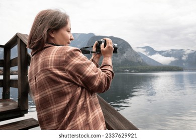 Woman-photographer in a plaid shirt filming a lake on a cloudy day, outdoor recreation concept, Austria - Powered by Shutterstock