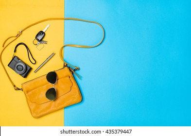 Woman's accessories lying flat on textured fabric background. Blue and yellow pastel colors with copy space around products. Horizontal image or photograph.