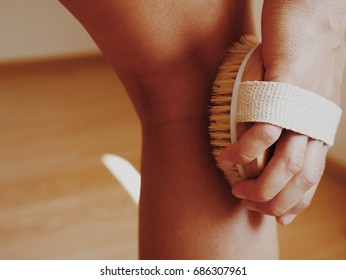 Woman's arm holding dry brush to top of her leg