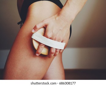 Woman's arm holding dry brush to top of her leg