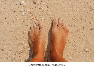 Woman's bare feet covered with sand on the beach.