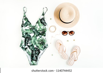 Woman's beach accessories: swimsuit with tropical print, rattan bag, straw hat on white background. Summer background. Flat lay, top view.