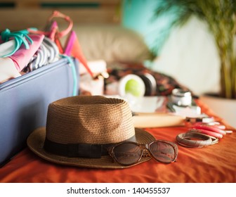 Woman's bedroom full of things ready to be taken on summer holiday.