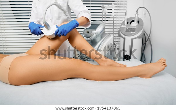 Woman\'s body slimming ultrasonic cavitation using\
ultrasound cavitation machine with a cosmetologist. Anti-cellulite\
therapy for female leg