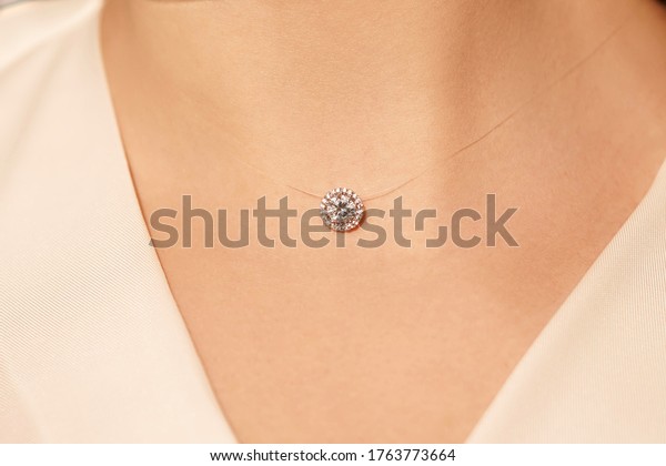 Woman\'s decollete with a luxury\
jewelry. Unusual and elegant pendant. Beauty and accessories.\
Silver pendant around the neck of a girl,  pendant with a\
stone