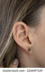 A woman's ear in close-up. Ear without lobe, earlobe type. Attached earlobes.