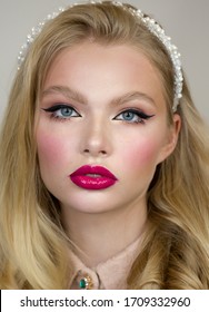 Woman's Face Close Up. Beauty Portrait. Bright Makeup, Pink Lips, Long Bunches Of Eyelashes On The Lower Eyelid And Black Arrows. She Somtrit Straight. Clean And Healthy Skin. Blush On Cheeks. Blonde.