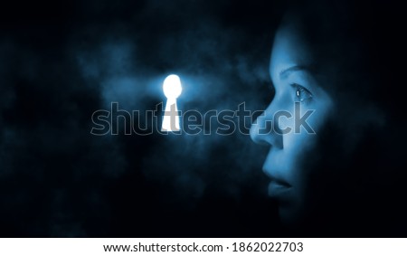 the woman's face in the dark looks through the keyhole glowing blue mysterious light