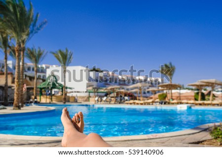 womans feet against swimming pool on resting