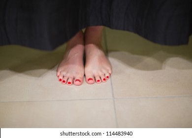 Womans Feet Behind Changing Room Curtain In Shopping Mall