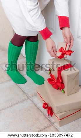 Woman's feet in green Socks stand near the White Door with Gifts on the eve of holidays Christmas and New Year.