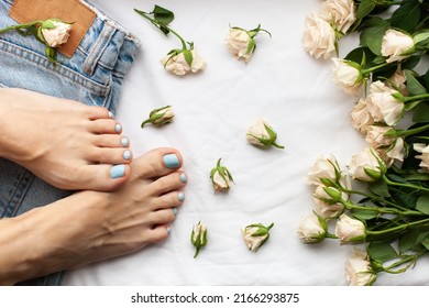 Womans Feet, Jeans And Roses On A White Background. Blue Nail Polish Pedicure. Pedicure Beauty Salon, Foot Care Concept.