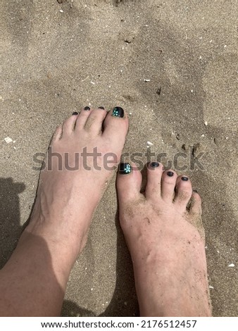 woman's feet on the sand, at the sea, dirty with sand, with black nails