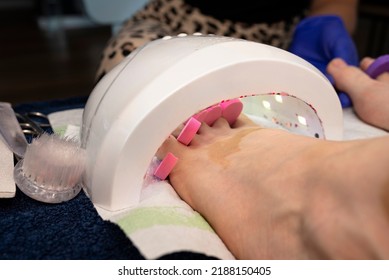 Womans Feet With Painted Hybrid Nails Hardened Under A UV Lamp.