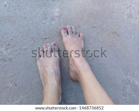 Woman's feet with painted nails on the sand of beach