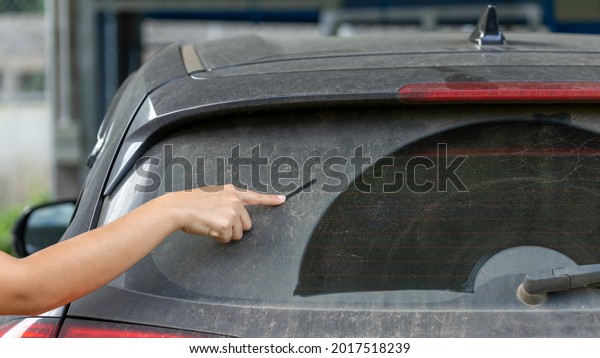 Woman\'s\
finger pointing to car window Car dust is not cleaned, there are\
thick dust stains. Ideas for cleaning your\
car