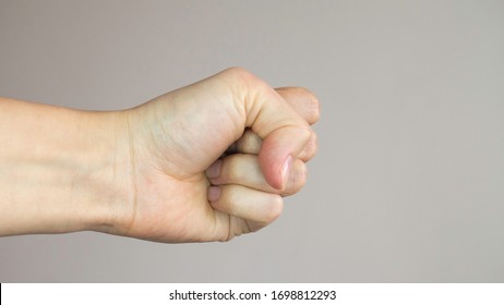 Woman's fist isolated on a light gray background.