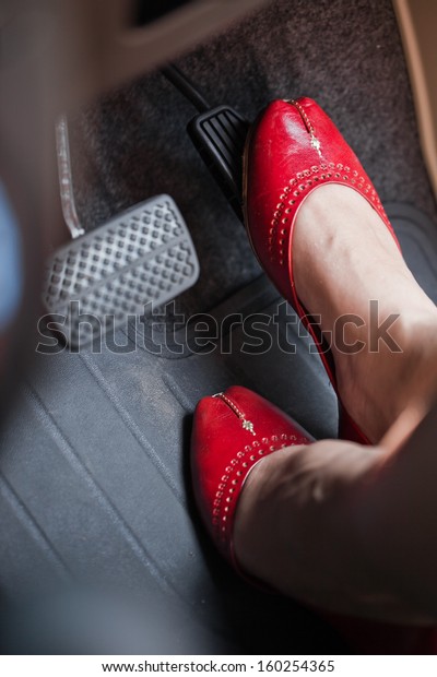 A\
woman\'s foot depressing the brake pedal of a\
car.