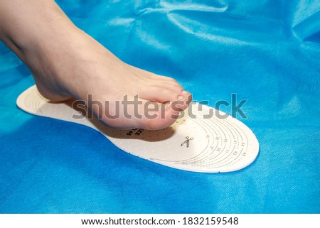 A woman's foot stands on a universal Shoe insole to take measurements. Close-up, selective focus.