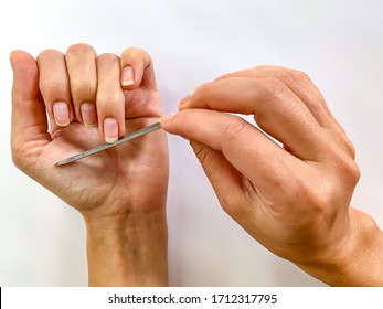 Woman's Girl's Hand Filing Nails With Metal Nail File On A White Background. Self Manicure At Home