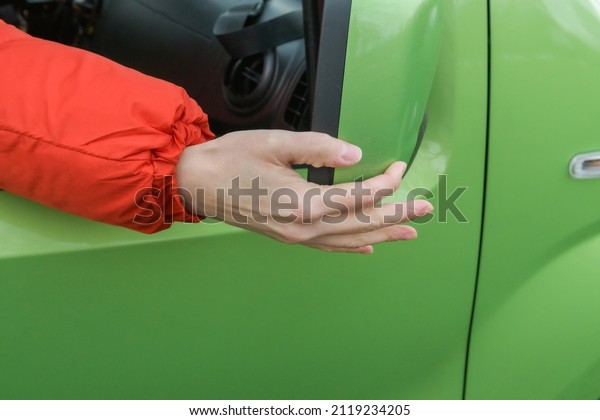 Woman\'s hand\
adjusts the rearview mirror in the\
car