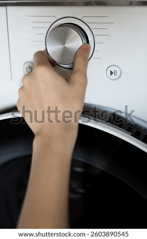 woman's hand adjusts the washing program in the washing machine